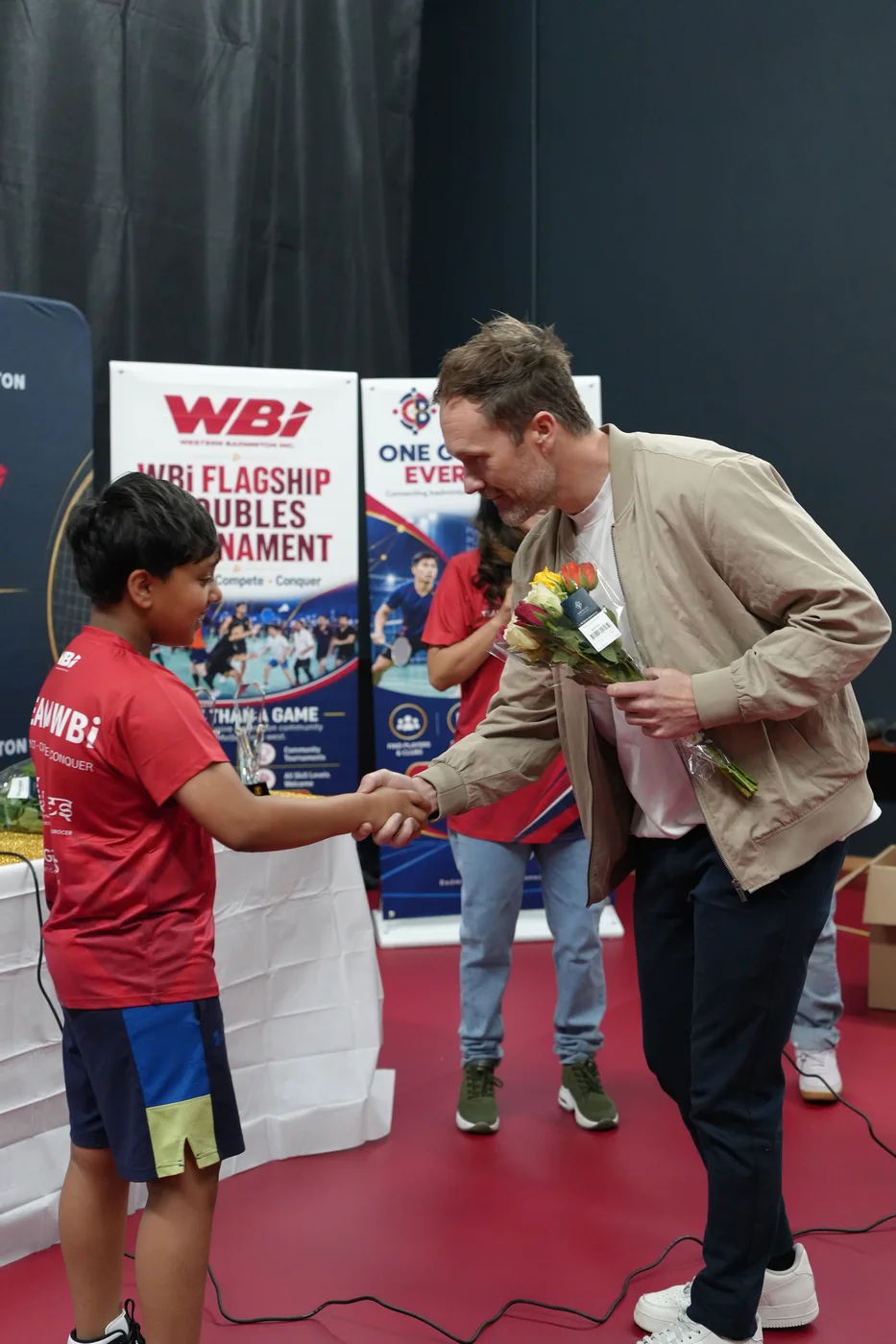 Clint receiving flowers and shaking hands with a young Team WBi member